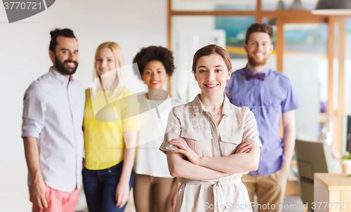 Image of happy young woman over creative team in office