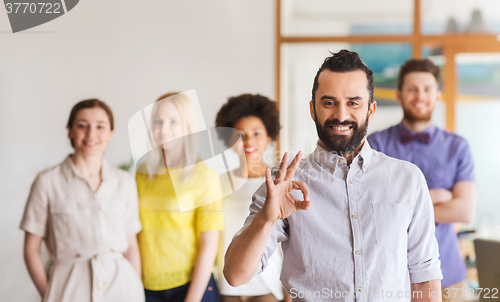 Image of happy young man over creative team in office