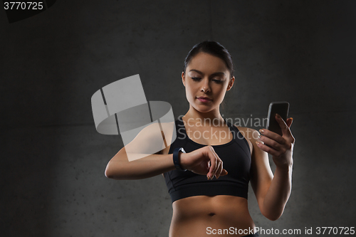 Image of woman with heart-rate watch and smartphone in gym