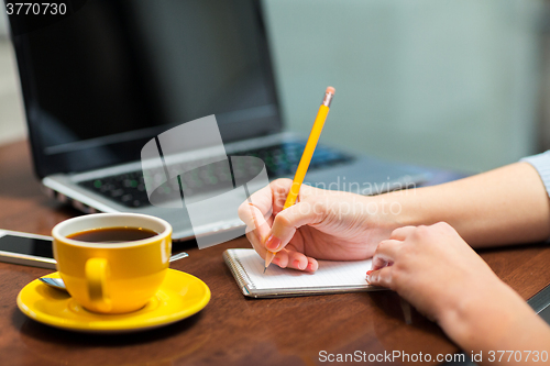 Image of close up of woman writing to notebook with pencil