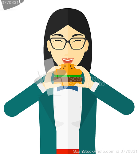 Image of Woman eating hamburger. 
