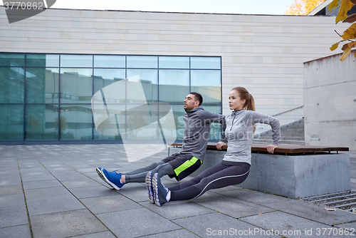 Image of couple doing triceps dip exercise outdoors