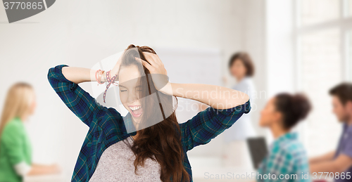 Image of happy student girl holding to head at school