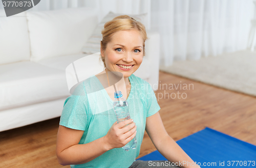 Image of happy woman drinking water and exercising at home