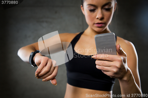 Image of woman with heart-rate watch and smartphone in gym