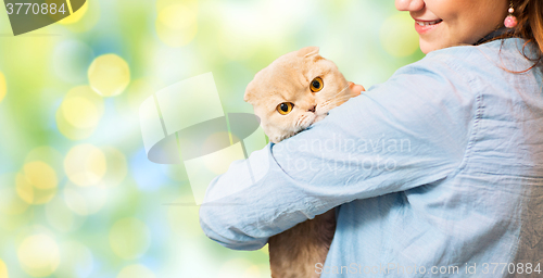 Image of happy woman holding scottish fold cat over green