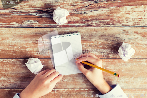 Image of close up of hands with notebook and pencil