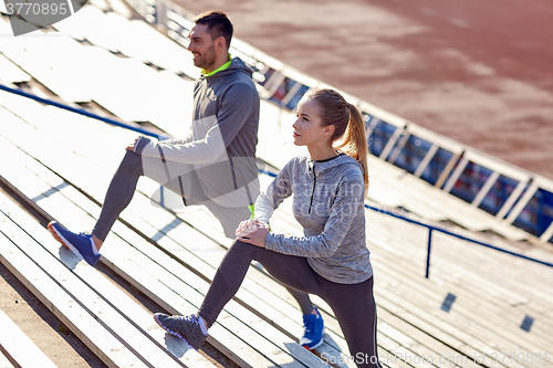 Image of couple stretching leg on stands of stadium