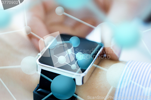 Image of close up of hands with molecules on smartwatch