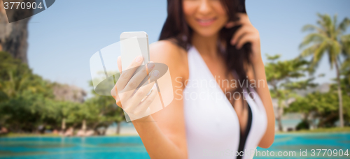 Image of young woman taking selfie with smartphone on beach