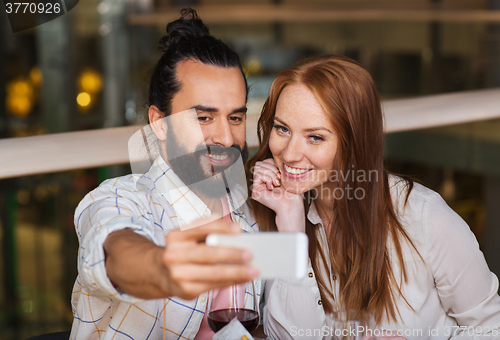 Image of couple taking selfie by smartphone at restaurant