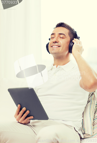 Image of smiling man with tablet pc and headphones at home