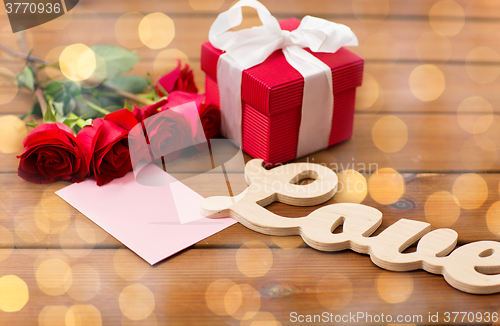 Image of close up of gift box, red roses and greeting card