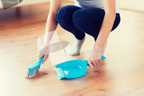 Image of close up of woman with brush and dustpan sweeping