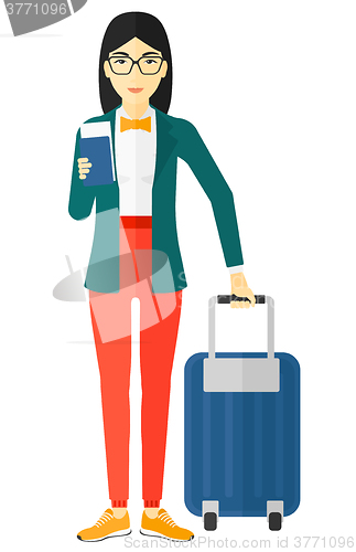Image of Woman standing with suitcase and holding ticket.