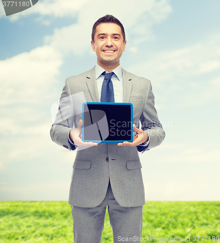Image of happy businessman in suit showing tablet pc screen