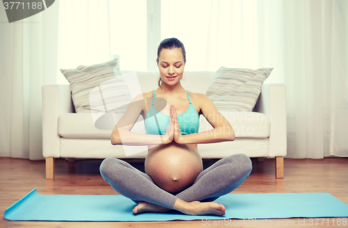 Image of happy pregnant woman meditating at home