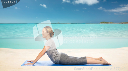 Image of woman making yoga in dog pose on beach 