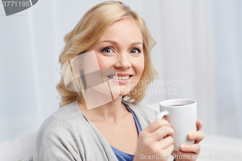 Image of smiling woman with cup of tea or coffee at home