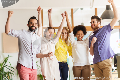 Image of happy creative team celebrating victory in office