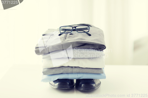 Image of close up of folded male shirts and shoes on table