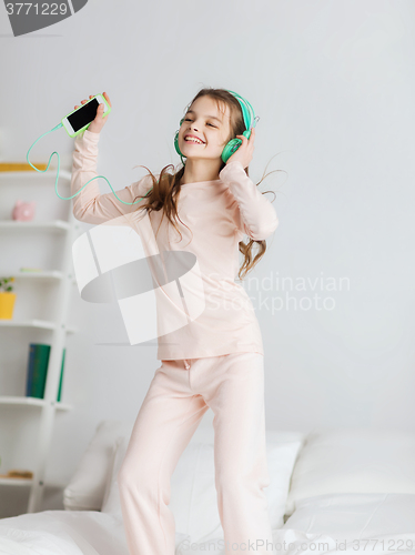 Image of girl jumping on bed with smartphone and headphones