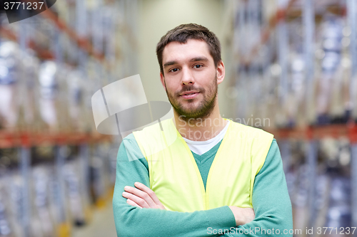 Image of happy man in reflective safety vest at warehouse