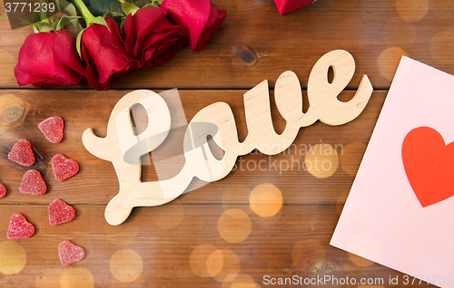 Image of close up of gift box, red roses and greeting card