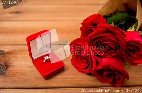 Image of close up of diamond engagement ring and red roses