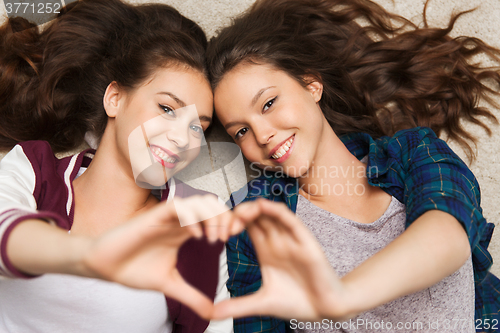 Image of happy smiling pretty teenage girls lying on floor