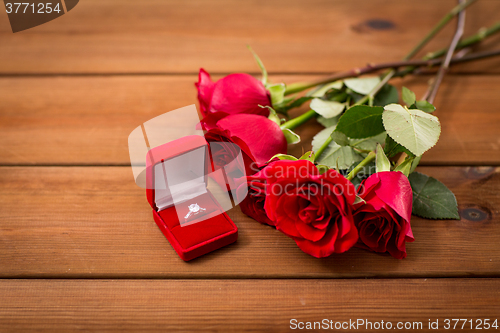 Image of close up of diamond engagement ring and red roses