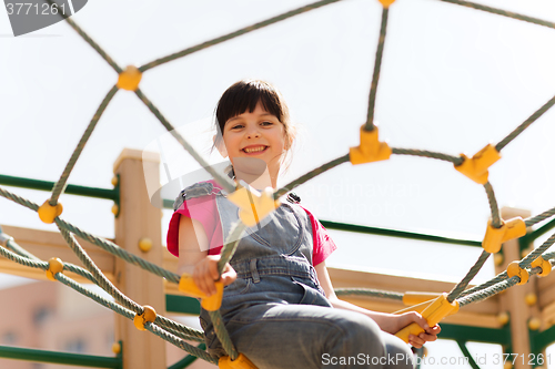 Image of happy little girl climbing on children playground