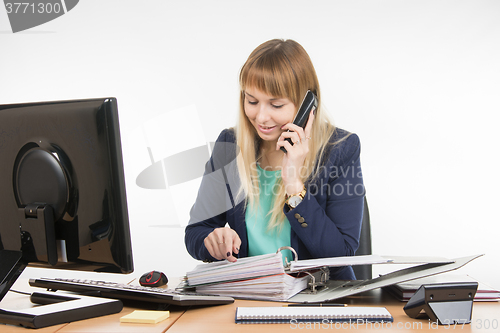 Image of Business woman reads the contents of the document the other party on the phone