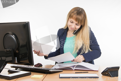 Image of Business woman talking on the phone and looking at the paper documents