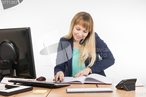 Image of Business woman talking on the phone, looking for the right information at the office book