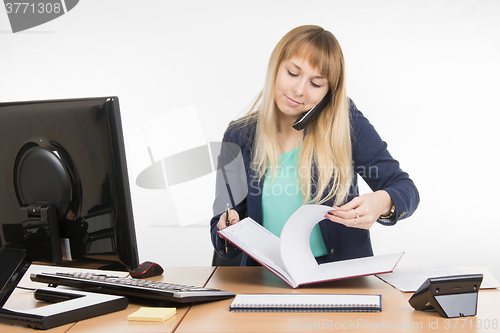 Image of Business woman answering the phone delves into folders with documents