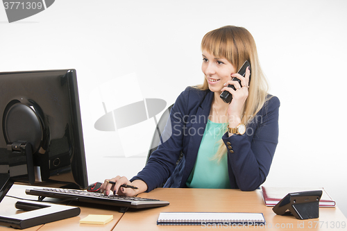 Image of Business woman working in the computer and talking on the phone