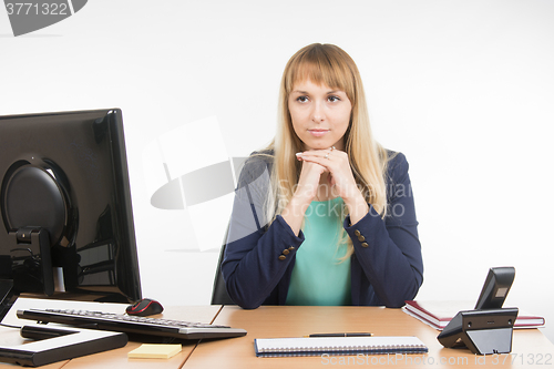 Image of Strict office a specialist sitting at a desk and looking at visitor