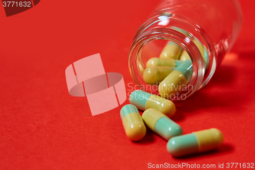 Image of Pills spilling out of pill bottle on red. Top view with copy space. 