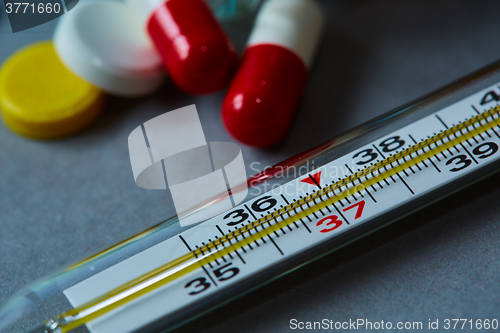 Image of Mercury thermometer and medical pills on background