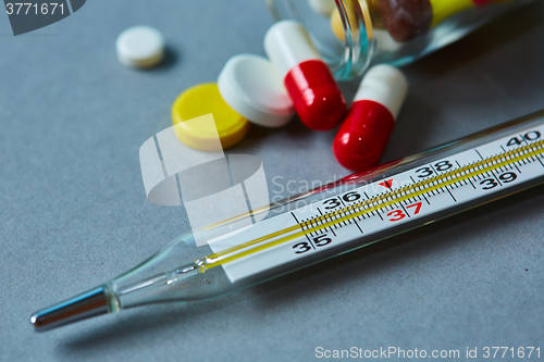 Image of Mercury thermometer and medical pills on background