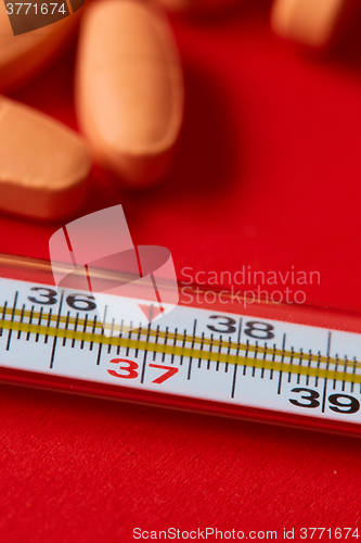 Image of Mercury thermometer and medical pills on background