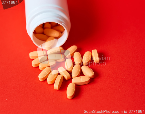 Image of Pills spilling out of pill bottle on red. Top view with copy space. 