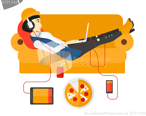 Image of Woman with gadgets lying on sofa.