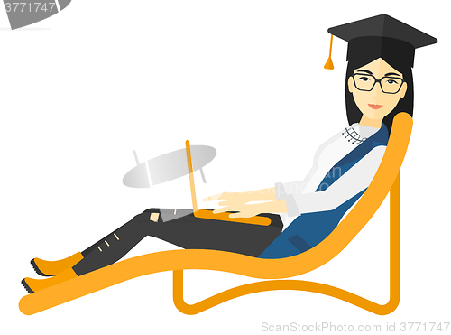 Image of Graduate lying in chaise lounge with laptop.