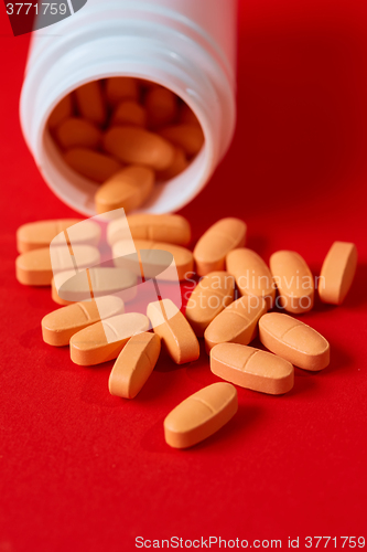 Image of Pills spilling out of pill bottle on red. Top view with copy space. 