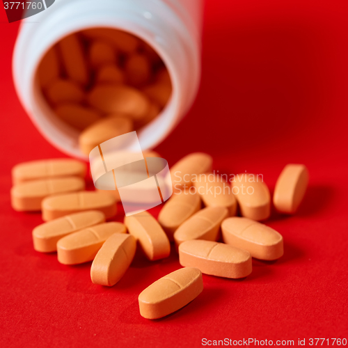 Image of Pills spilling out of pill bottle on red. Top view with copy space. 