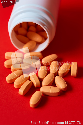 Image of Pills spilling out of pill bottle on red. Top view with copy space. 