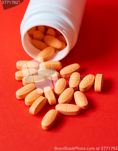 Image of Pills spilling out of pill bottle on red. Top view with copy space. 