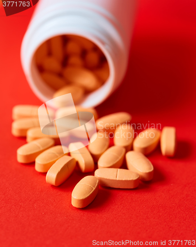 Image of Pills spilling out of pill bottle on red. Top view with copy space. 